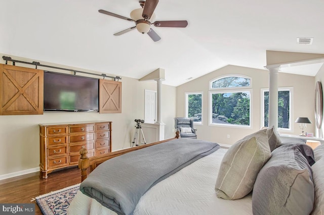 bedroom featuring decorative columns, vaulted ceiling, wood finished floors, and baseboards