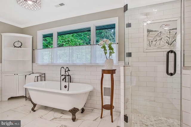 bathroom with marble look tile flooring, a freestanding bath, a stall shower, and ornamental molding
