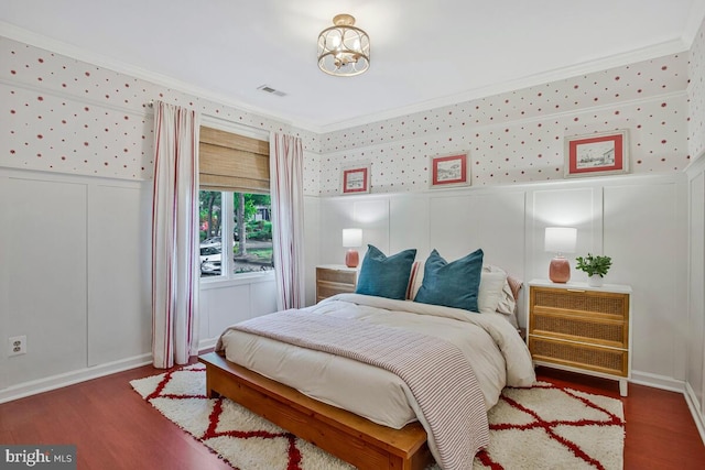 bedroom featuring a decorative wall, wood finished floors, crown molding, a chandelier, and wallpapered walls