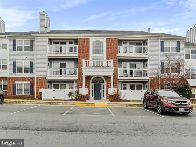 view of building exterior with fence and uncovered parking