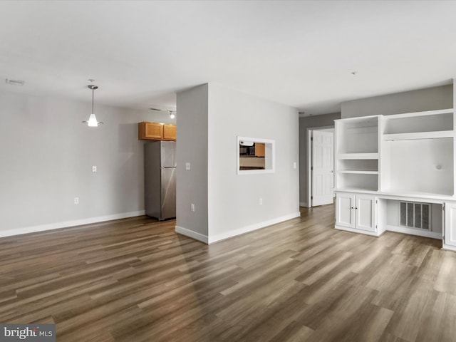 unfurnished living room with visible vents, baseboards, and wood finished floors