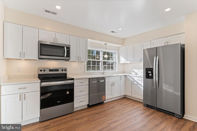 kitchen with white cabinetry, stainless steel appliances, visible vents, and a sink