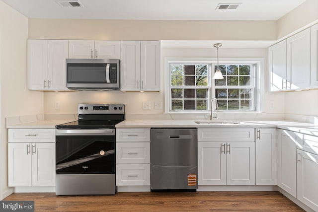 kitchen featuring visible vents, appliances with stainless steel finishes, white cabinetry, and a sink