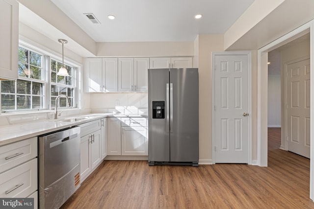 kitchen featuring a sink, light wood-type flooring, visible vents, white cabinetry, and appliances with stainless steel finishes