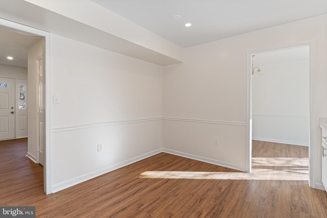 spare room with baseboards, wood finished floors, and recessed lighting