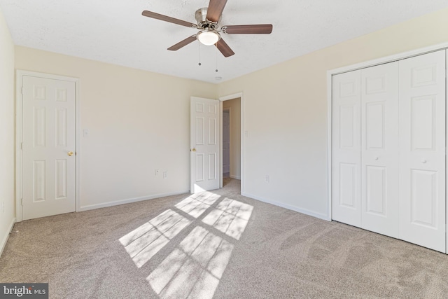 unfurnished bedroom with a closet, carpet flooring, baseboards, and a ceiling fan