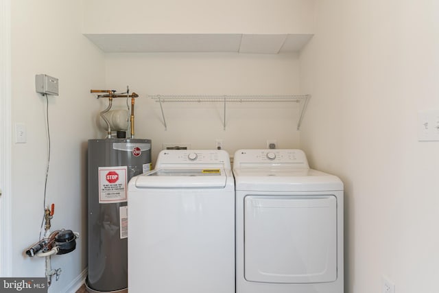 clothes washing area featuring water heater, washer and clothes dryer, and laundry area