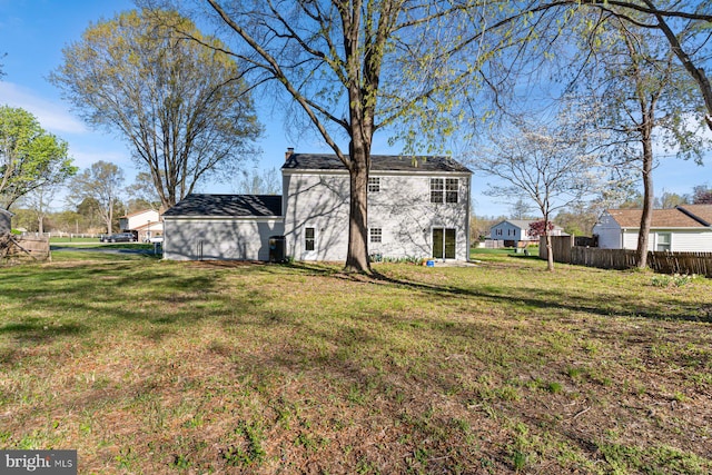 rear view of house featuring a chimney, fence, a yard, and brick siding