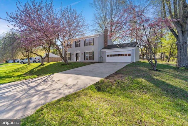 colonial home featuring driveway, a chimney, a front yard, and a garage