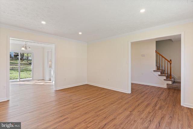 empty room featuring light wood-style floors, ornamental molding, baseboards, and a notable chandelier