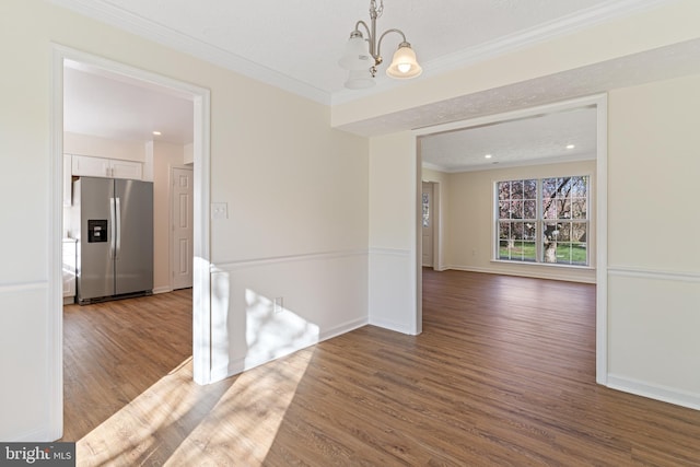 unfurnished dining area featuring wood finished floors, a chandelier, baseboards, ornamental molding, and recessed lighting