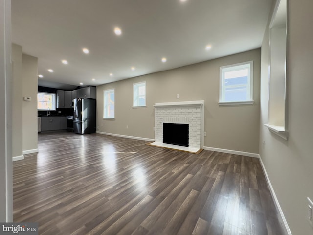 unfurnished living room with dark wood-type flooring, recessed lighting, and baseboards
