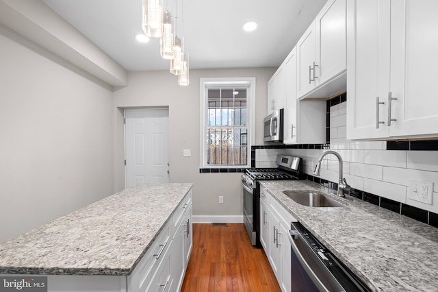738 N Patterson Park Ave, Baltimore, MD 21205 - kitchen featuring backsplash, baseboards, dark wood finished floors, appliances with stainless steel finishes, and a sink