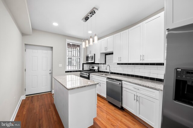 738 N Patterson Park Ave, Baltimore, MD 21205 - kitchen featuring backsplash, a kitchen island, appliances with stainless steel finishes, white cabinetry, and a sink