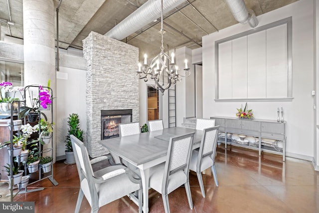 dining area featuring baseboards, an inviting chandelier, a fireplace, and concrete flooring