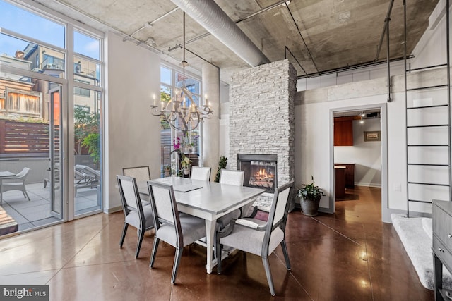 dining space featuring baseboards, a stone fireplace, finished concrete flooring, and a towering ceiling