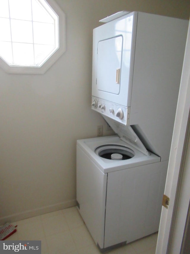 laundry area featuring stacked washer / drying machine and baseboards