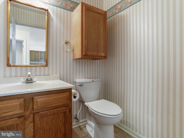 half bath featuring toilet, wallpapered walls, vanity, and tile patterned flooring