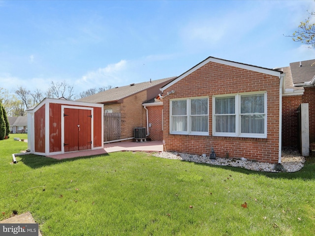 rear view of property with an outbuilding, a yard, a patio, a storage unit, and brick siding
