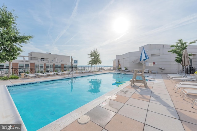 community pool with a patio area and fence
