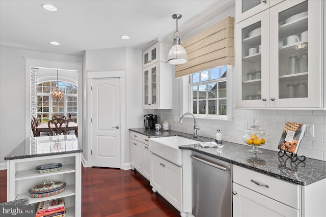 kitchen featuring a sink, dark stone countertops, tasteful backsplash, stainless steel dishwasher, and dark wood finished floors