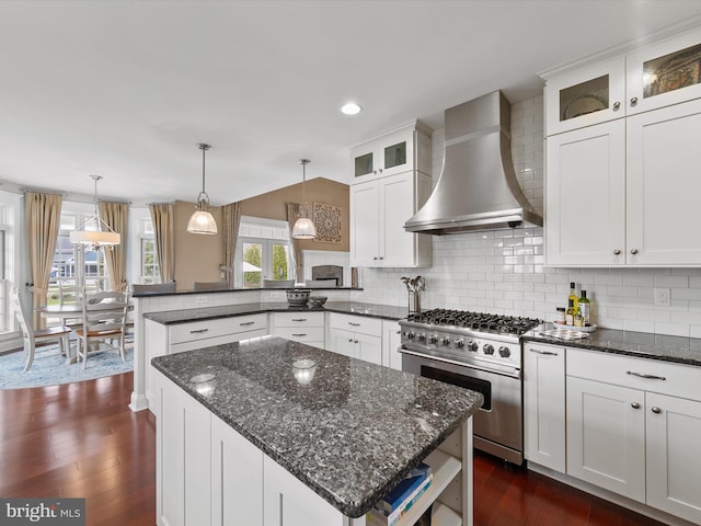 kitchen with dark wood-style floors, stainless steel range, wall chimney range hood, and a peninsula