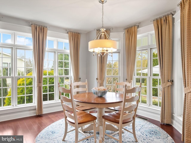 dining space with visible vents, plenty of natural light, a notable chandelier, and dark wood finished floors