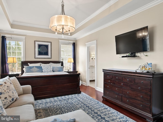 bedroom with connected bathroom, crown molding, baseboards, a tray ceiling, and dark wood-style flooring