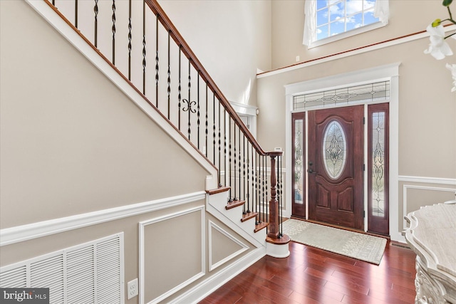 foyer with a decorative wall, stairs, a wainscoted wall, and wood finished floors