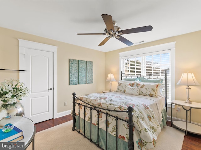 bedroom with ceiling fan, wood finished floors, visible vents, and baseboards