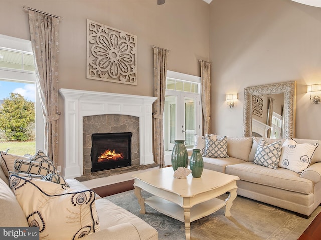 living room featuring a tile fireplace, a high ceiling, and wood finished floors