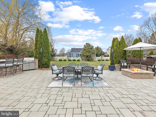view of patio with outdoor dining area, a fire pit, area for grilling, and fence