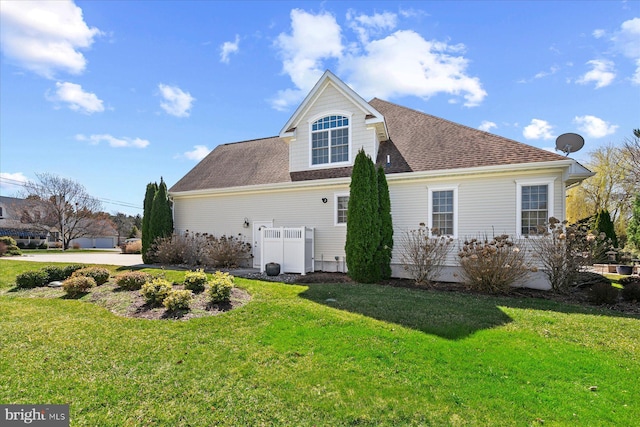 view of side of property with a yard and roof with shingles