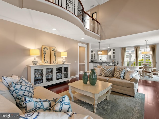 living area featuring recessed lighting, wood finished floors, baseboards, and a towering ceiling