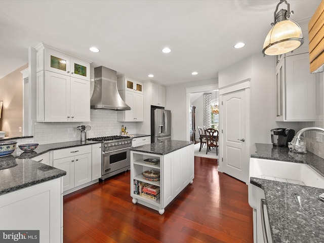 kitchen featuring dark wood finished floors, wall chimney range hood, white cabinetry, and appliances with stainless steel finishes