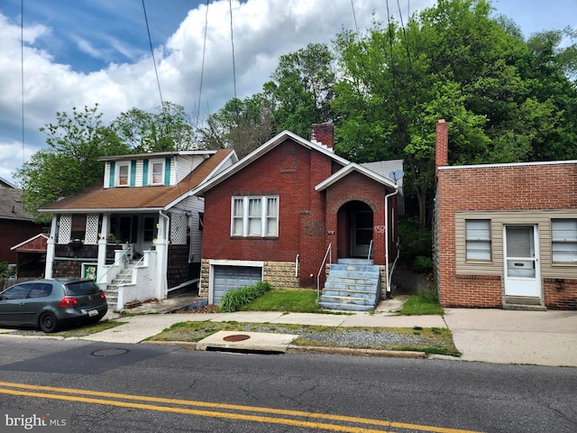 view of front of home with brick siding, driveway, an attached garage, and a chimney