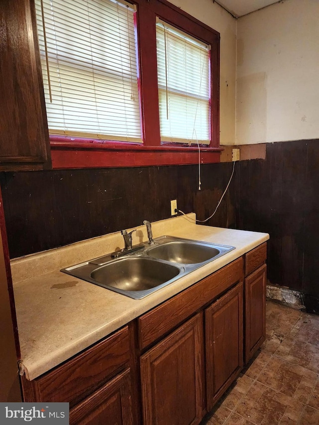 kitchen with light countertops, a wainscoted wall, and a sink