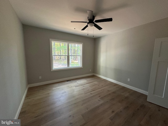 unfurnished room with ceiling fan, baseboards, and wood finished floors