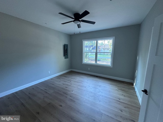 unfurnished bedroom with a ceiling fan, electric panel, wood finished floors, and baseboards