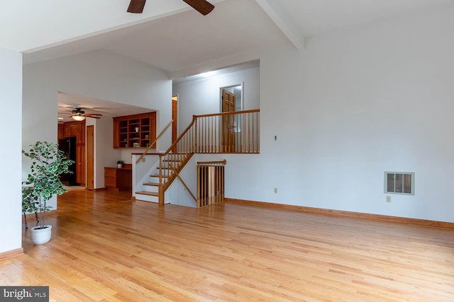 unfurnished living room featuring visible vents, light wood-style flooring, a ceiling fan, and stairway