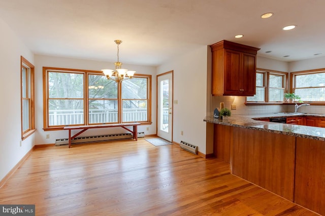 kitchen with light wood finished floors, dark stone countertops, a baseboard heating unit, and a sink