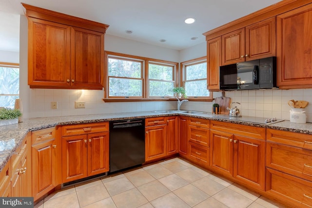 kitchen with brown cabinets, a sink, black appliances, and light stone counters