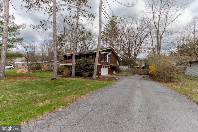 view of front of house with a chimney, driveway, a garage, and a front yard