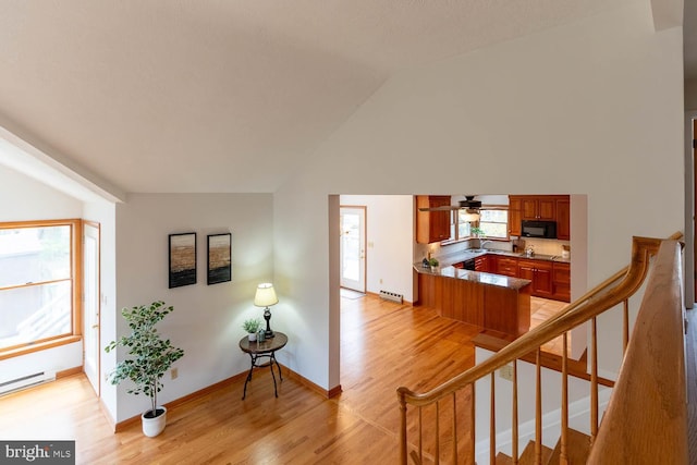 stairway featuring wood finished floors, a baseboard heating unit, lofted ceiling, a baseboard radiator, and baseboards