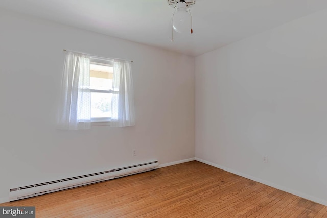 spare room featuring light wood finished floors, a baseboard radiator, baseboards, and ceiling fan