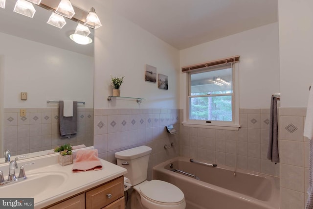 full bath featuring a garden tub, vanity, toilet, wainscoting, and tile walls