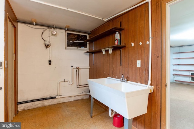 washroom featuring tile patterned floors, wooden walls, and a sink