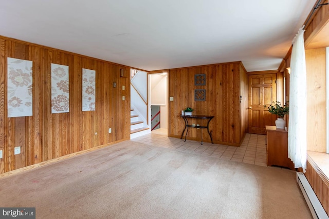 spare room featuring wooden walls, stairway, carpet, and baseboard heating