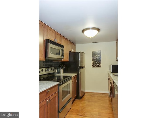 1023 Clinton St Unit 204, Philadelphia, PA 19107 - kitchen featuring tasteful backsplash, stainless steel appliances, light countertops, baseboards, and light wood finished floors
