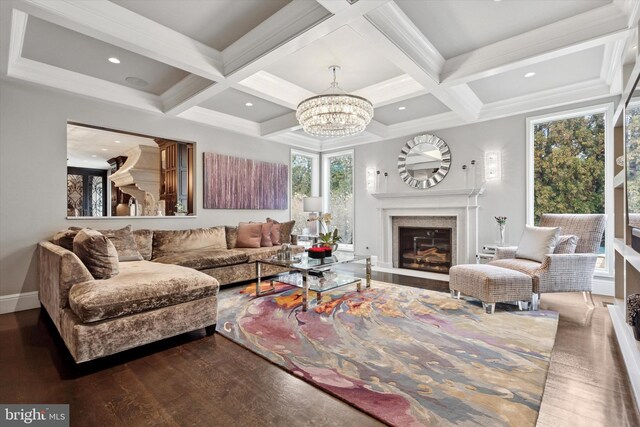 living area with a fireplace with flush hearth, beamed ceiling, wood finished floors, and a notable chandelier